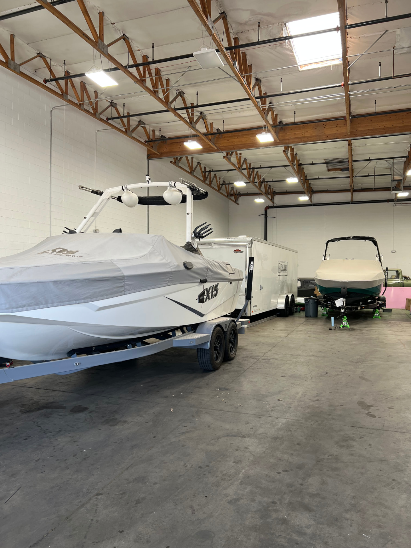 Boats and enclosed trailers inside the SPARKS Trailer Repair indoor facility in Gilbert, AZ